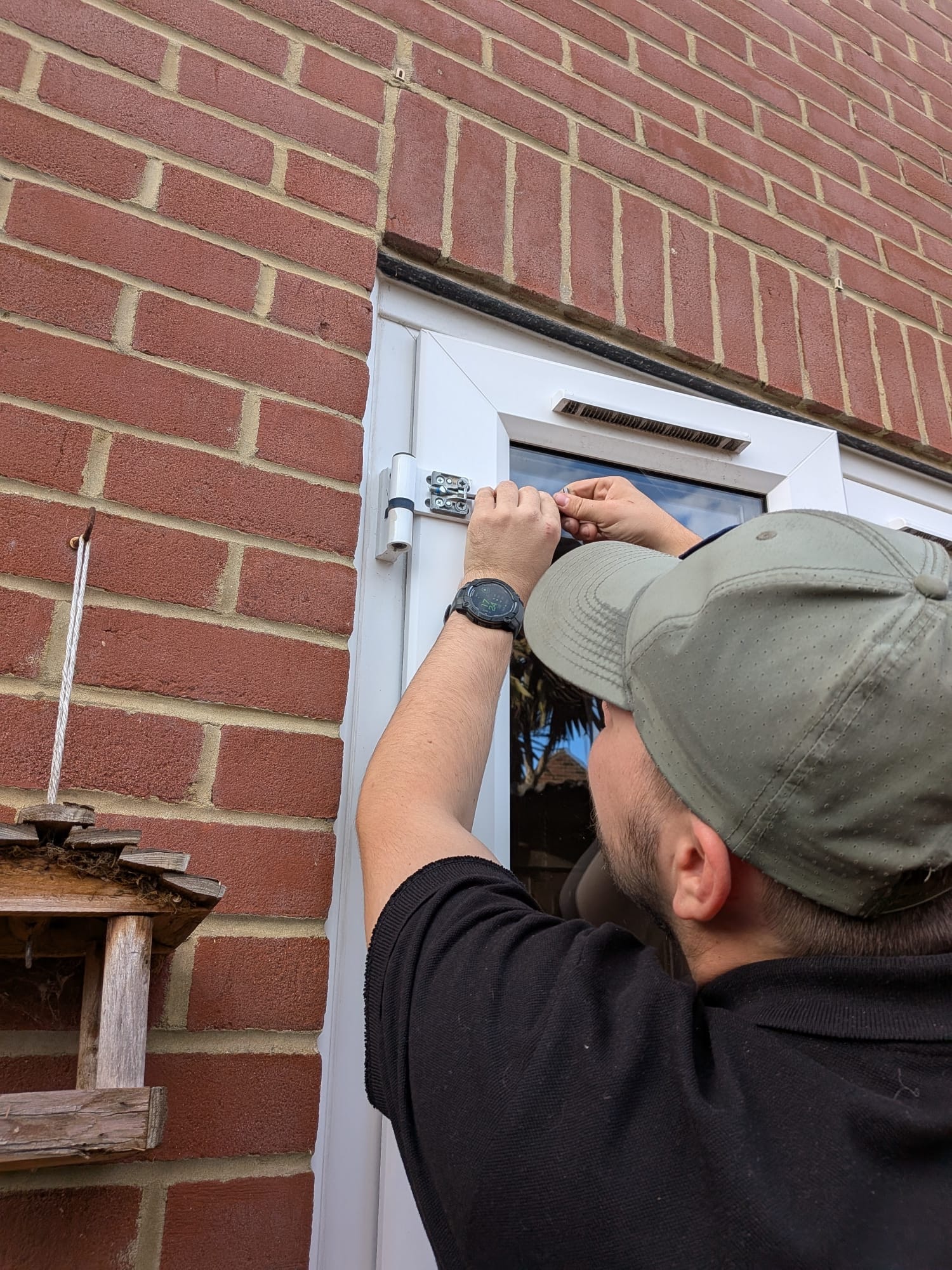 ClearAccess Locksmiths — adjusting a uPVC door hinge on a brick building